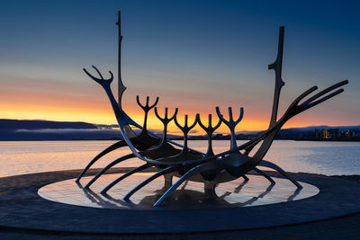 Close-up of silhouette table against sea during sunset