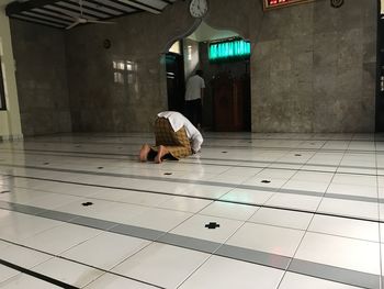 Rear view of man sitting on floor against building