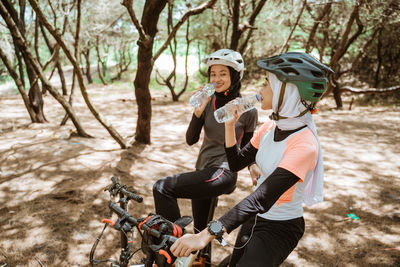 Smiling female cyclists drinking water at park