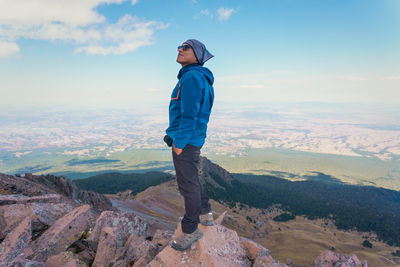 Rear view of man standing on mountain against sky