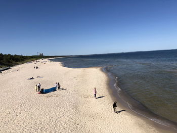 People on beach against clear sky