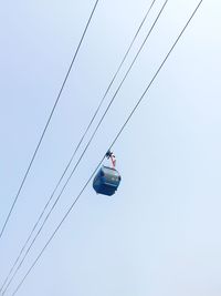 Low angle view of overhead cable cars against clear sky