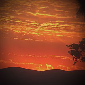 Scenic view of silhouette mountains against orange sky