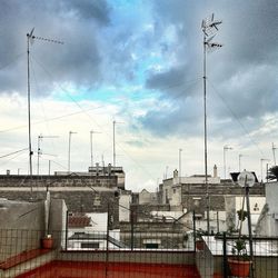 Low angle view of power lines against cloudy sky