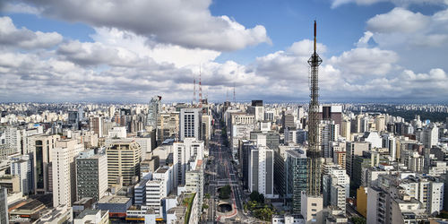 Aerial view of buildings in city against cloudy sky