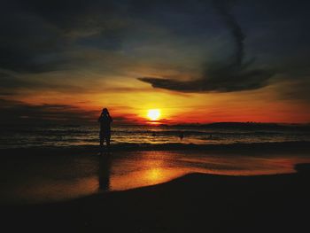 Silhouette man on beach against sky during sunset