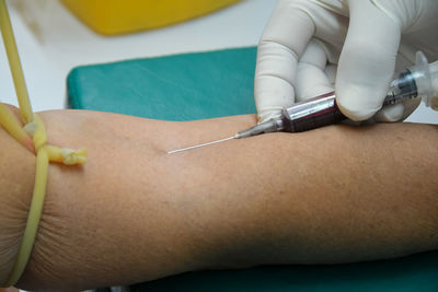 Cropped hands injecting patient in hospital