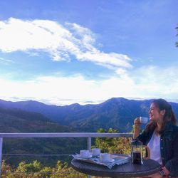 Woman sitting at restaurant against mountains