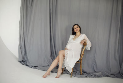 Happy pregnant woman sitting on chair