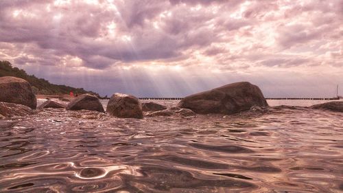 Rocks on beach against sky during sunset