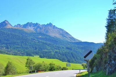 Road leading towards mountains against clear sky