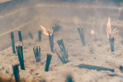 Close-up of burning candles on sand