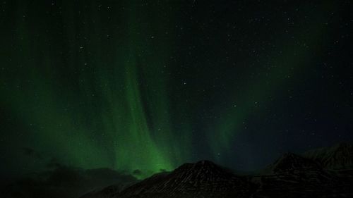 Low angle view of mountain against  aurora at night