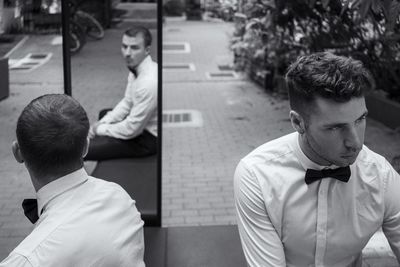 Well dressed men sitting on bench with reflection in mirror