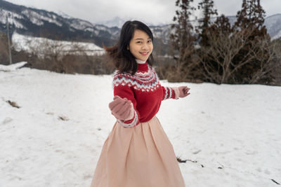 Portrait of smiling woman standing on snow covered land