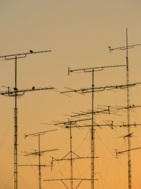 Low angle view of silhouette antenna against clear sky during sunset