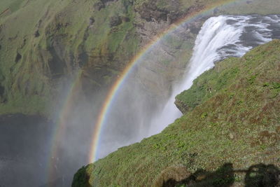 Scenic view of rainbow over waterfall