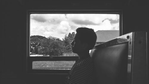 Rear view of woman looking through window