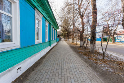 Empty footpath amidst buildings in city