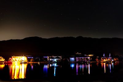 Scenic view of illuminated lake against sky at night