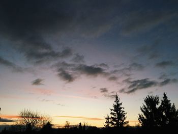 Low angle view of silhouette trees against dramatic sky