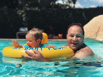 Portrait of happy boy and father playing in swimming pool