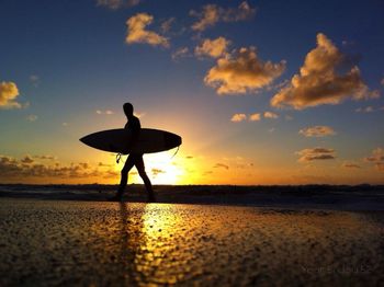 Silhouette of woman standing on beach at sunset