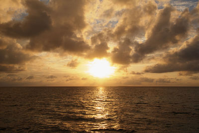 Scenic view of sea against cloudy sky at sunset