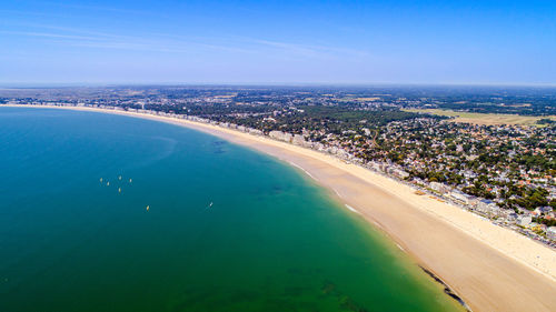 Aerial view of sea and cityscape against blue sky