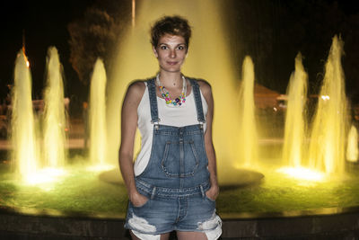 Portrait of woman against orange waterfall at night