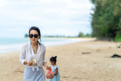 Young women wearing sunglasses standing on beach