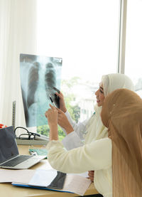 Woman using mobile phone while sitting on table