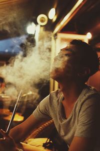 Young man smoking while sitting in bar