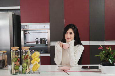 Portrait of young woman sitting on table at home