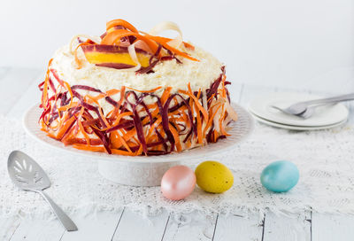 A triple layered carrot cake decorated with buttercream icing and carrot ribbons