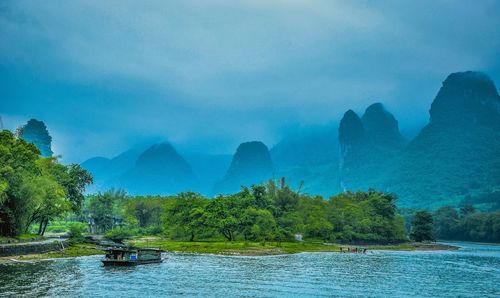 Scenic view of lake by mountains against cloudy sky