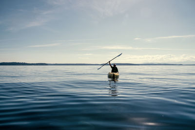 Silhouette man kayaking in sea against sky