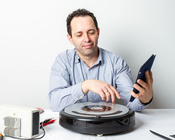 Portrait of man holding camera over white background