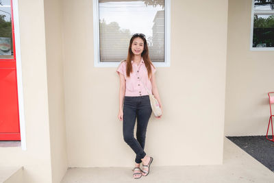 Portrait of woman standing against wall