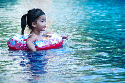 Cute girl with inflatable ring in swimming pool