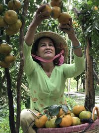 Portrait of woman with fruits on tree