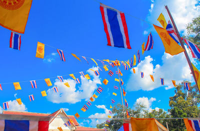 Low angle view of thai flags against sky