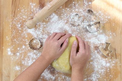 Cropped hands kneading dough on wooden table