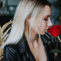 Close-up of young woman smelling red rose