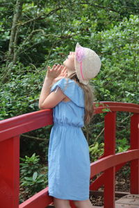 Girl standing by railing against trees