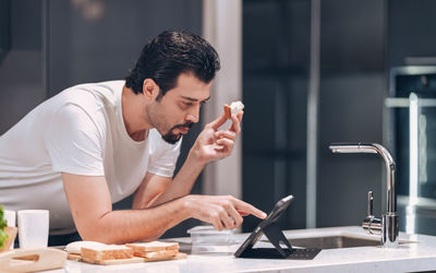 Young man spending time on their tablet on morning in the kitchen