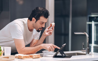 Young man using mobile phone at table