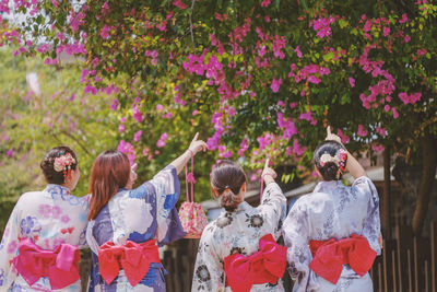 Rear view of women pointing towards tree