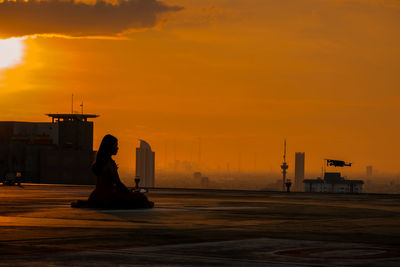 Rear view of silhouette people at beach against sky during sunset