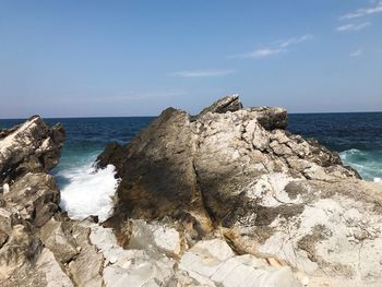 Rock formations on shore against sky